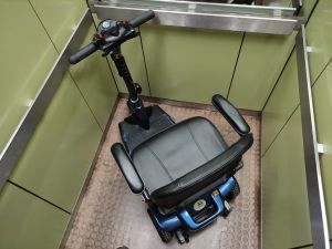 Scooter eléctrico modelo Smart de 3 ruedas dentro de un ascensor de pequeñas dimensiones